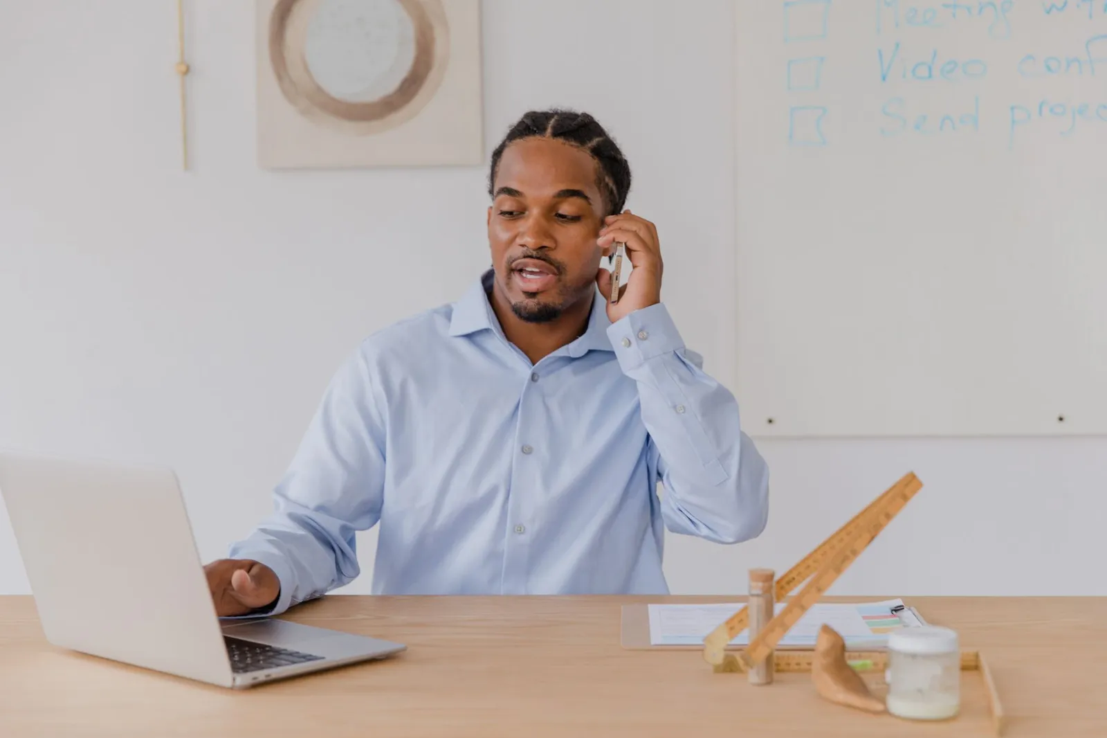 Business owner on a phone call at a desk with a laptop open, discussing a website project remotely