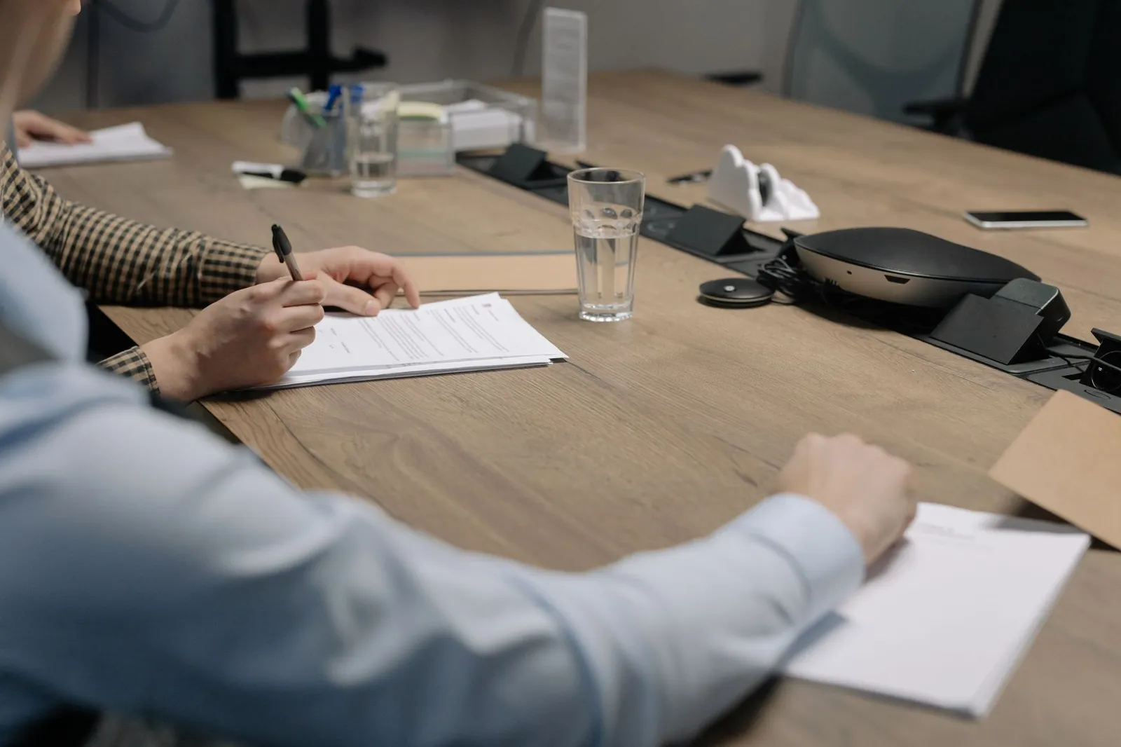 Client signing a written project quote across the table at a meeting — every package starts with a fixed price in writing
