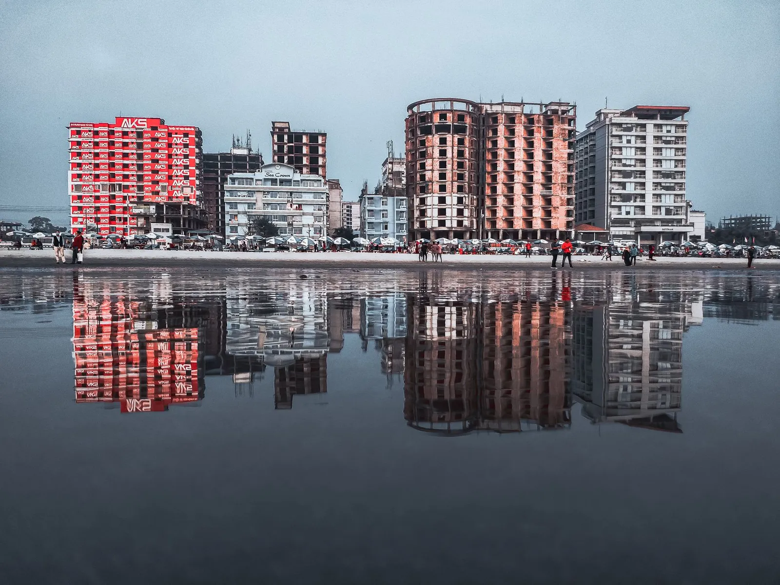 Beachfront hotel buildings reflected on wet sand at Cox's Bazar at dusk — businesses whose bookings often start with a Google search