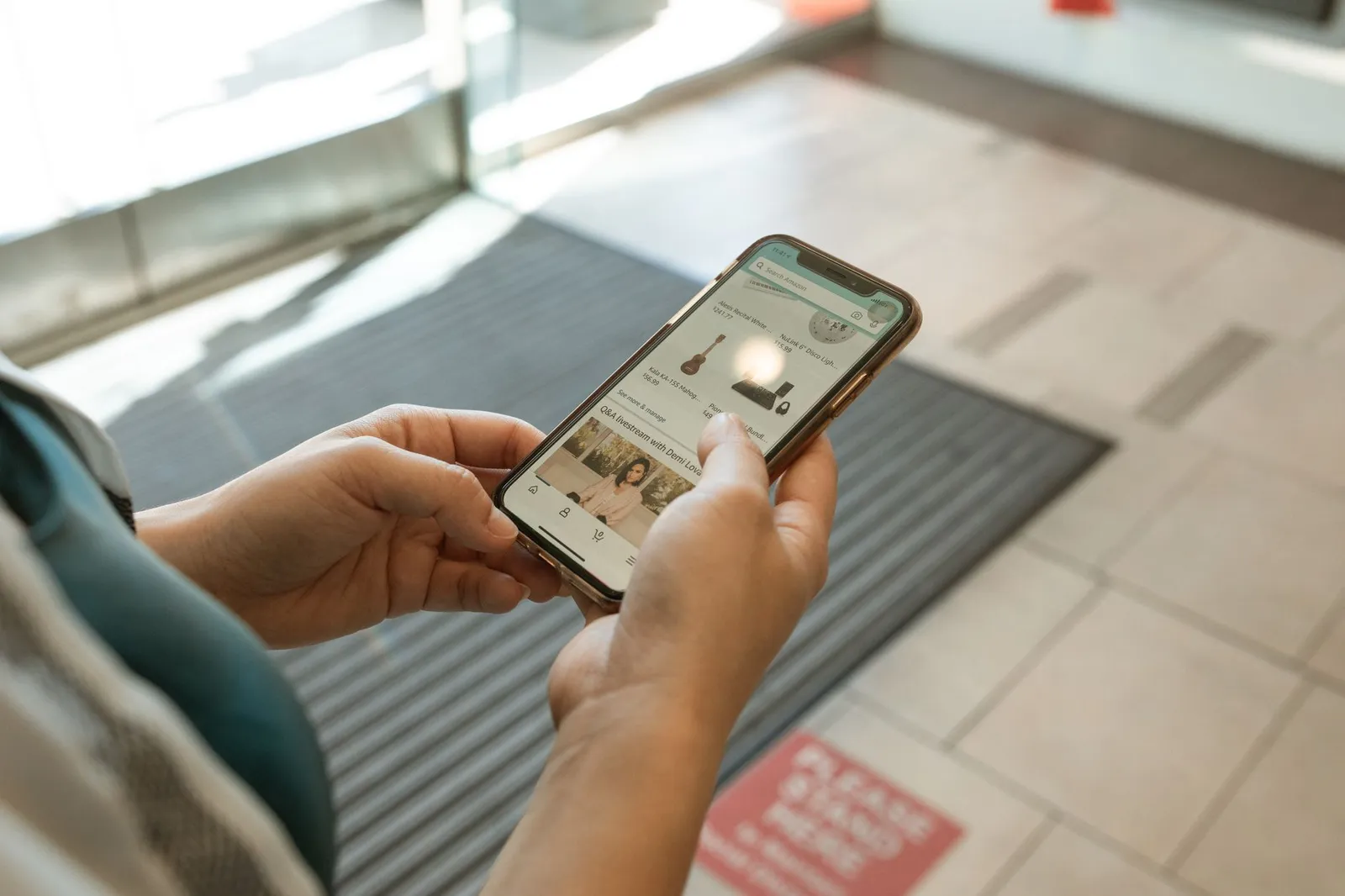 Customer holding a smartphone with a shopping app open — the kind of repeat order a local business app is built for