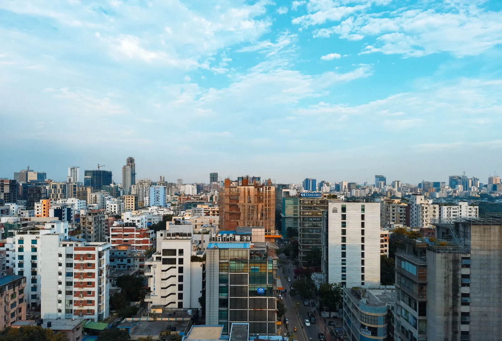 Dhaka skyline of office and apartment towers under a blue sky — the city a remote web designer in Dhaka builds business websites for