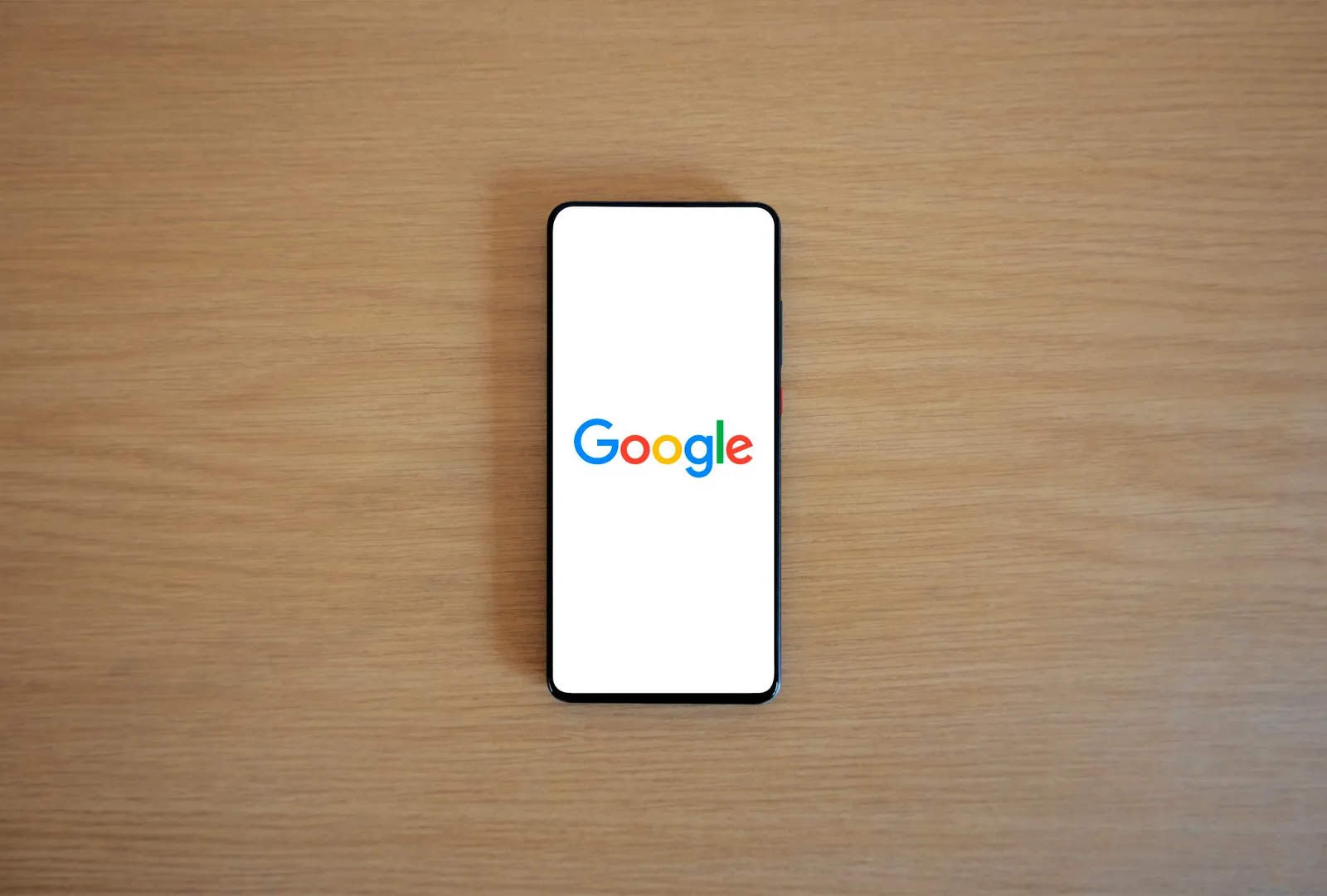 Smartphone showing the Google search screen on a wooden table — where Mymensingh customers start looking for a supplier or service
