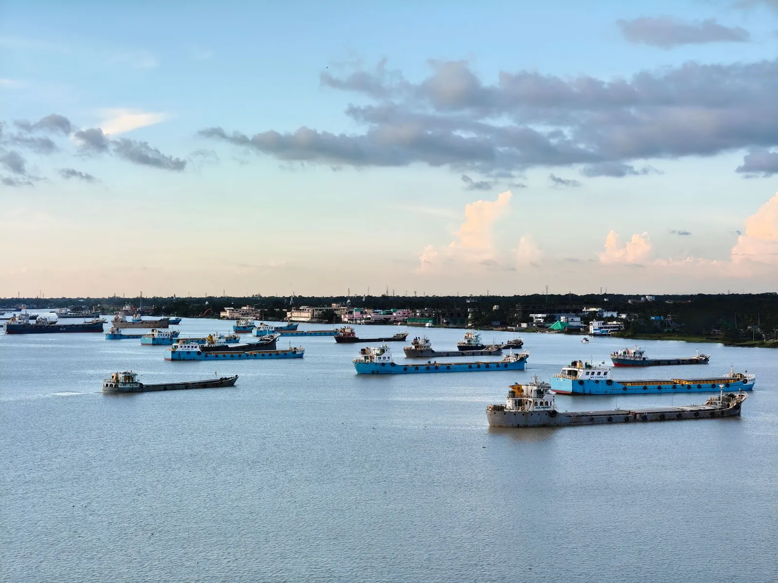 Cargo vessels at anchor on a river in Khulna under an evening sky — the trading region a web designer in Khulna builds websites for