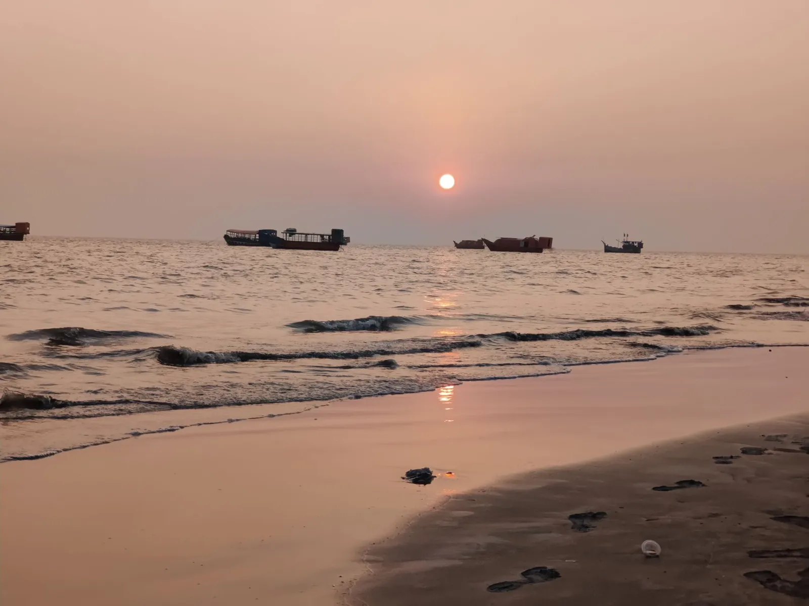 Sunset over Kuakata beach with fishing boats offshore — the kind of destination travellers search for before booking a hotel