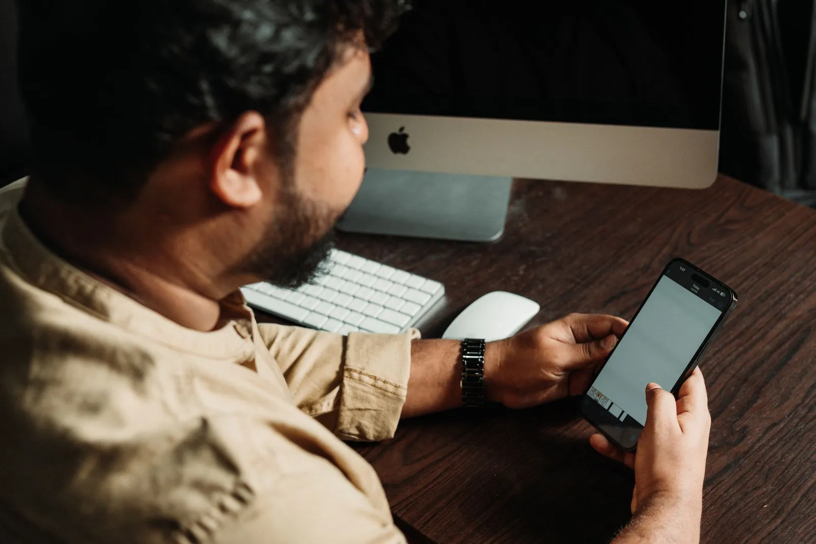 Man checking his smartphone at a desk — where most customers start looking for a local business