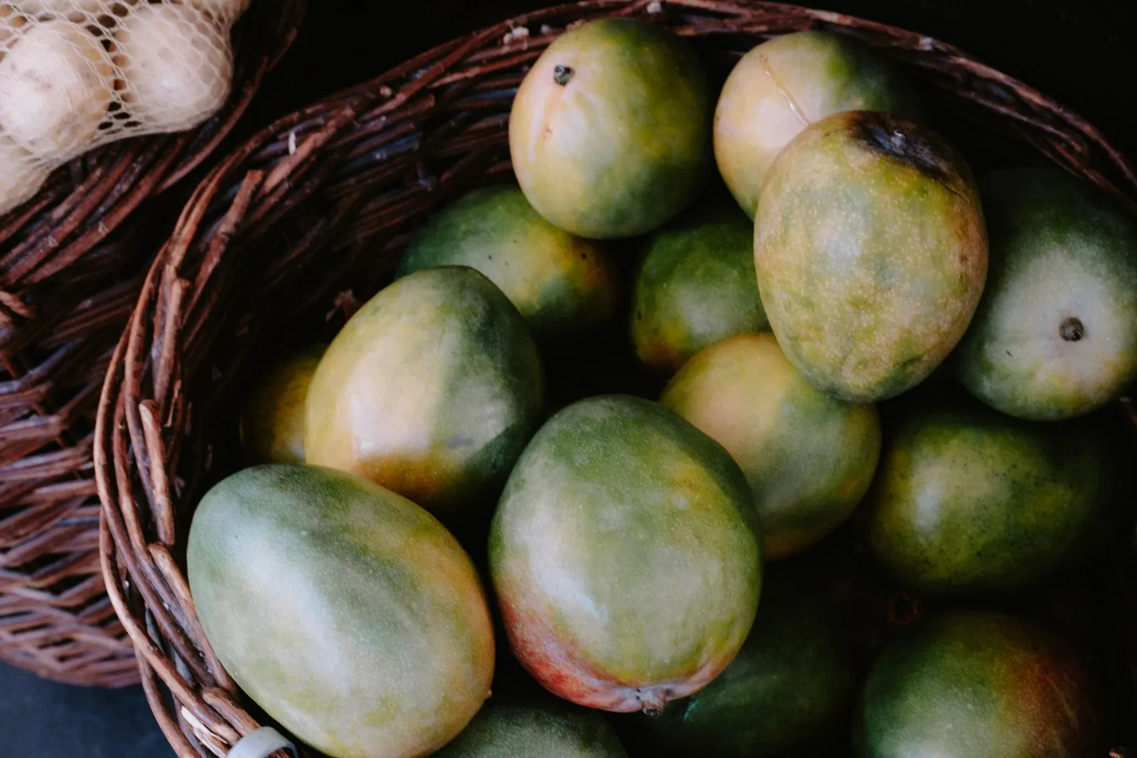 Ripe mangoes piled in a woven basket — the kind of seasonal product repeat buyers order again through a shopping app