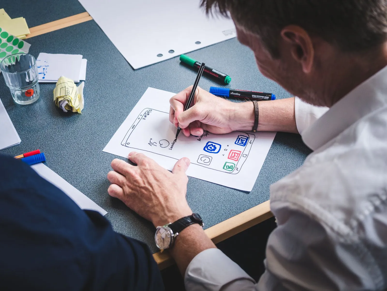 Designer sketching mobile app screens on paper before any code is written
