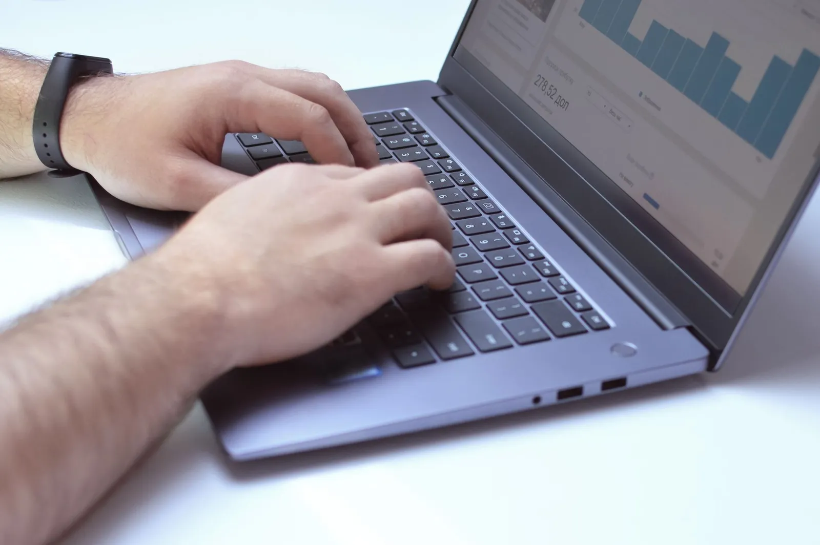 Hands on a laptop keyboard with an analytics chart on screen — reading search data before deciding what to fix