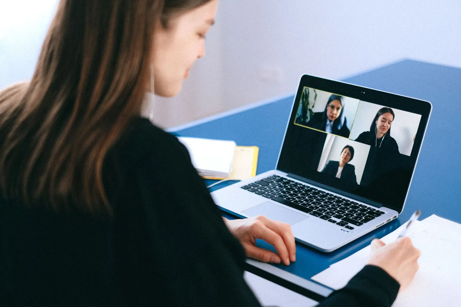 Business owner taking notes during a video meeting on a laptop — how remote website projects are reviewed