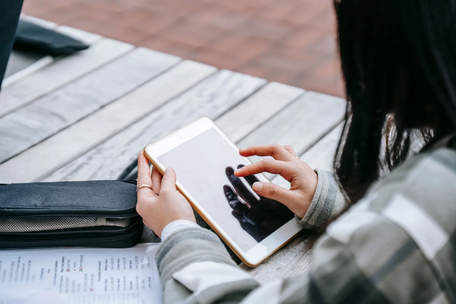 Student using a study app on a tablet at a table with notes — the daily notices and results a coaching centre app can deliver