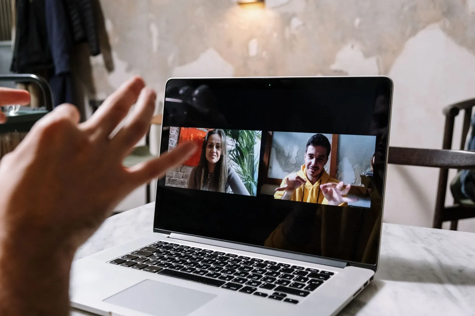 Video call on a laptop between a web designer and two clients, reviewing a website project remotely